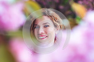 Young happy woman between cherry blossom portrait at spring