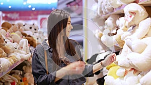Young happy woman choosing soft toy Teddy Bear for her child