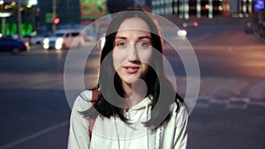 Young happy woman in city at night serious face portrait on blurred carlights background toned
