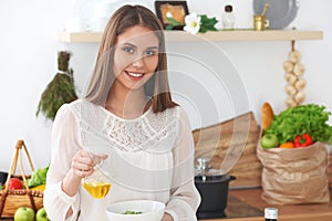 Young happy woman is cooking or eating fresh salad in the kitchen. Food and health concept