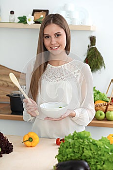 Young happy woman cooking in the kitchen. Healthy meal, lifestyle and culinary concepts. Good morning begins with fresh