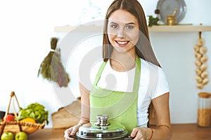 Young happy woman cooking soup in the kitchen. Healthy meal, lifestyle and culinary concept. Smiling student girl