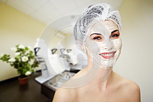 Young happy woman in cosmetic mask and hat smiles photo