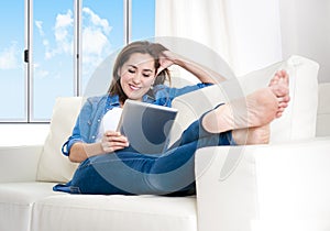 Young happy woman on couch at home enjoying using digital tablet