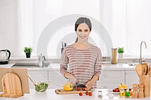 Young, happy woman cutting fresh vegetables