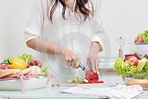 Young happy woman cutting vegetables