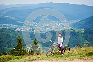 Young happy woman cycling on mountain bike at summer day
