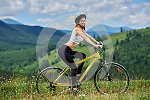 Young happy woman cycling on mountain bike at summer day