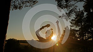 Young happy woman dancing and having fun in park at sunset