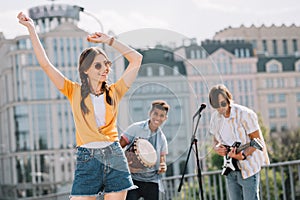 Young happy woman dancing to music played by buskers