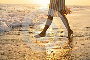 Young happy woman dancing turning around by sea in a yellow fluttering dress.