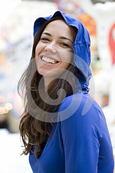 The young happy woman in a dark blue hood smiles