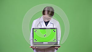 Young happy woman doctor showing laptop