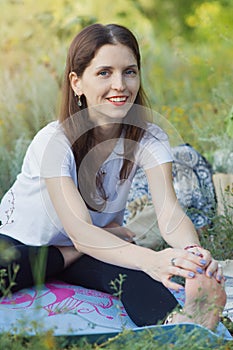 Young happy woman doing stretching exercises for meditation and yoga in nature. Outdoor sports concept, fitness