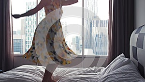 Young happy woman in dress jumping on hotel bed. slow motion. 3840x2160