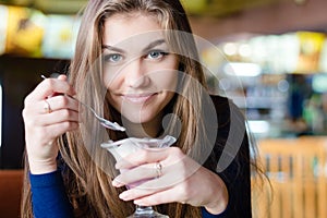 Young happy woman eating ice cream in cafe