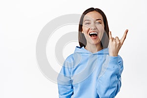 Young happy woman enjoying event, having fun at party, showing horns rock heavy metal gesture, laughing and smiling