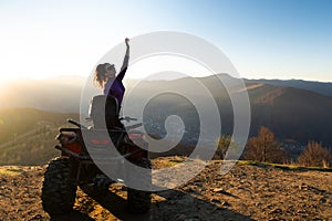 Young happy woman enjoying extreme ride on atv quad motorbike in autumn mountains at sunset