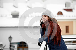 Young happy woman enjoying winter weather wearing scarf and knitted hat