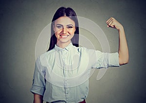 Young happy woman flexing muscles showing strength