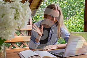 Young happy woman focuses on her laptop in wooden alcove. Relaxed outdoor setting emphasizes comfort and productivity