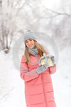 Young happy woman with a gift in her hands for Christmas in winter. woman in pink quilted coat beautiful winter