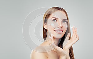 Young happy woman with healthy skin applying cosmetic cream. Skincare, beauty and facial treatment concept