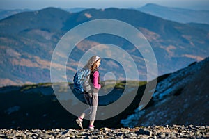 Young happy woman hiker is walking on mountain plato