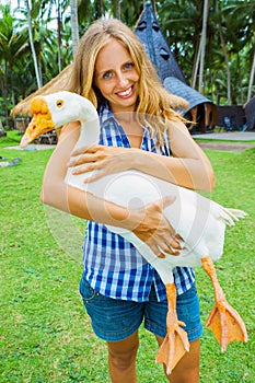 Young happy woman hold in hands funny pet - white goose