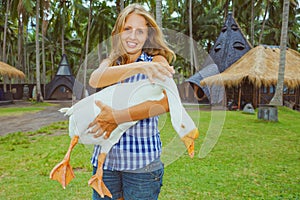 Young happy woman hold in hands funny pet - white goose