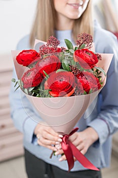 Young happy woman holding a beautiful bunch of red buttercups or Ranunculus in her hands. Present for a smiles girl