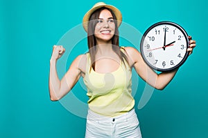 Young happy woman holding a clock with 2 clock on a green background