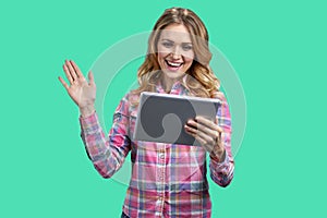 Young happy woman holding digital tablet and waving with hand.