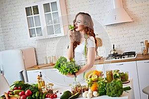 Young happy woman holding lettuce leaves for making salad in the beautiful kitchen with green fresh ingredients indoors. Healthy