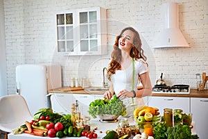 Young happy woman holding lettuce leaves for making salad in the beautiful kitchen with green fresh ingredients indoors. Healthy