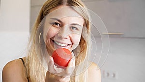 Young happy woman holding tomato and smiling