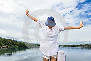 Young happy woman holding up her hands joyfully in front of a be