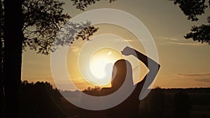 Young happy woman jumping, dancing and having fun in the forest at sunset