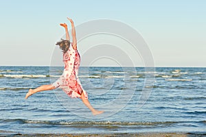 Young happy woman jumping high at seaside