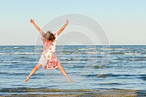 Young happy woman jumping high at seaside