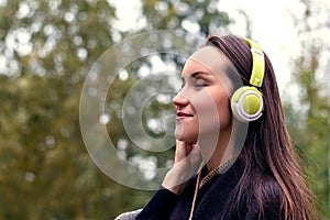 Young happy woman listening music from smartphone with headphones in a quiet Park