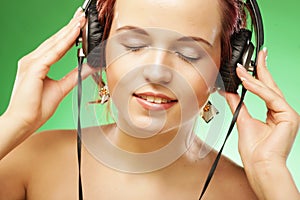 Young happy woman listening to music with headhones