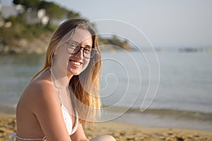 Young happy woman looks at camera on the beach
