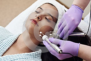 Young happy woman on modern cosmetic procedures. Skin care spa concept. Closeup Of Beautiful Woman Receiving Facial Microcurrent