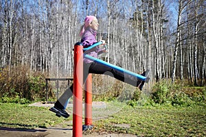 Young happy woman moves at simulator in park in photo