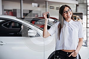 Young happy woman near the car with keys in hand