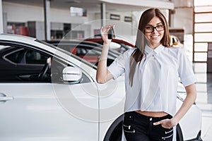 Young happy woman near the car with keys in hand