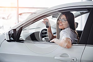 Young happy woman near the car with keys in hand