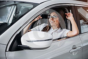 Young happy woman near the car with keys in hand