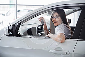 Young happy woman near the car with keys in hand